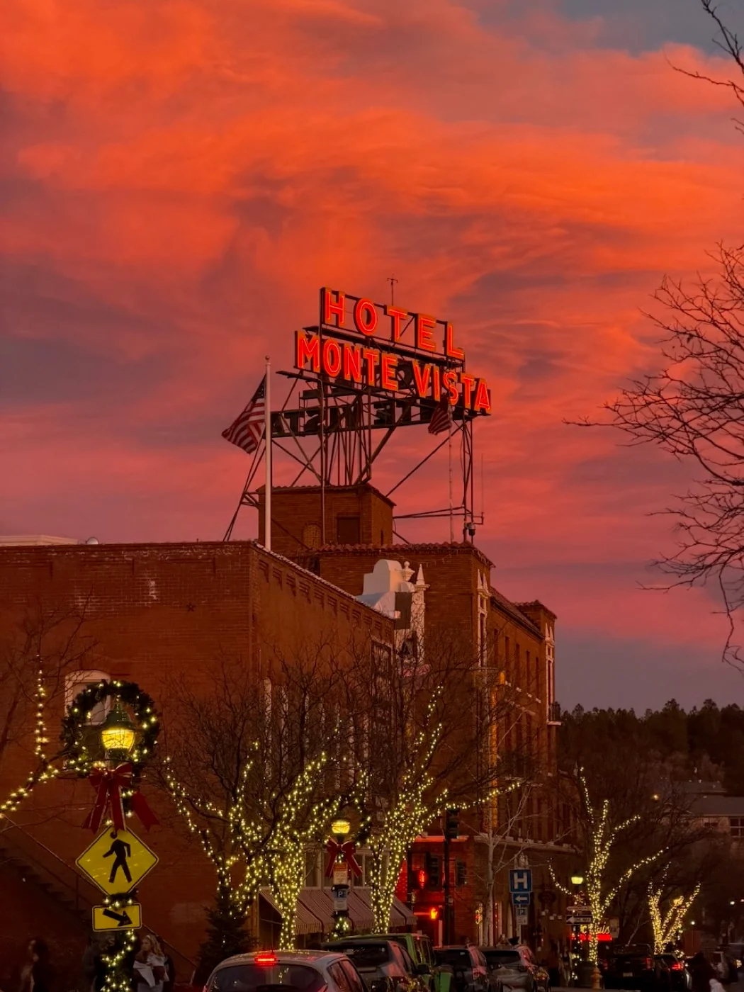 The red neon Hotel Monte Vista sign glowing above downtown Flagstaff as the sky darkens
